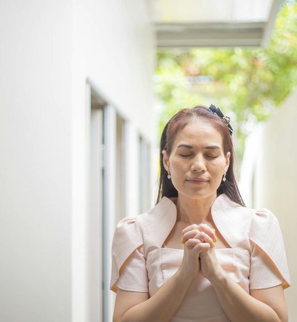 Person meditating outdoors with a serene natural background.